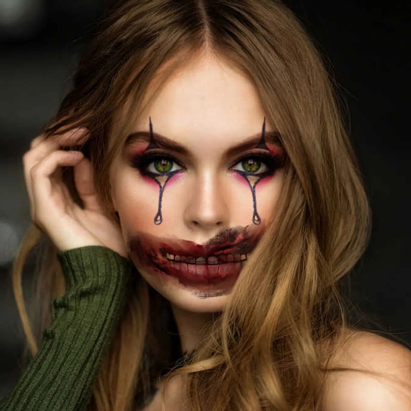 Woman with dramatic makeup and a green sweater against a dark background