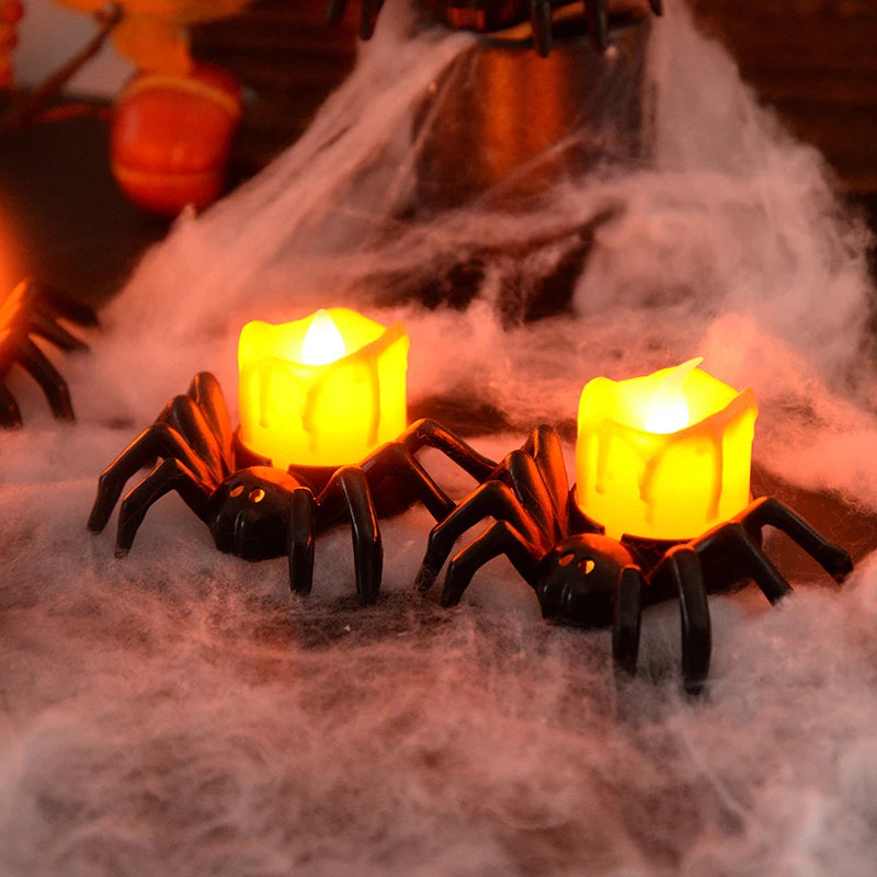 Two spider-shaped candles with glowing yellow lights on a spider web background.