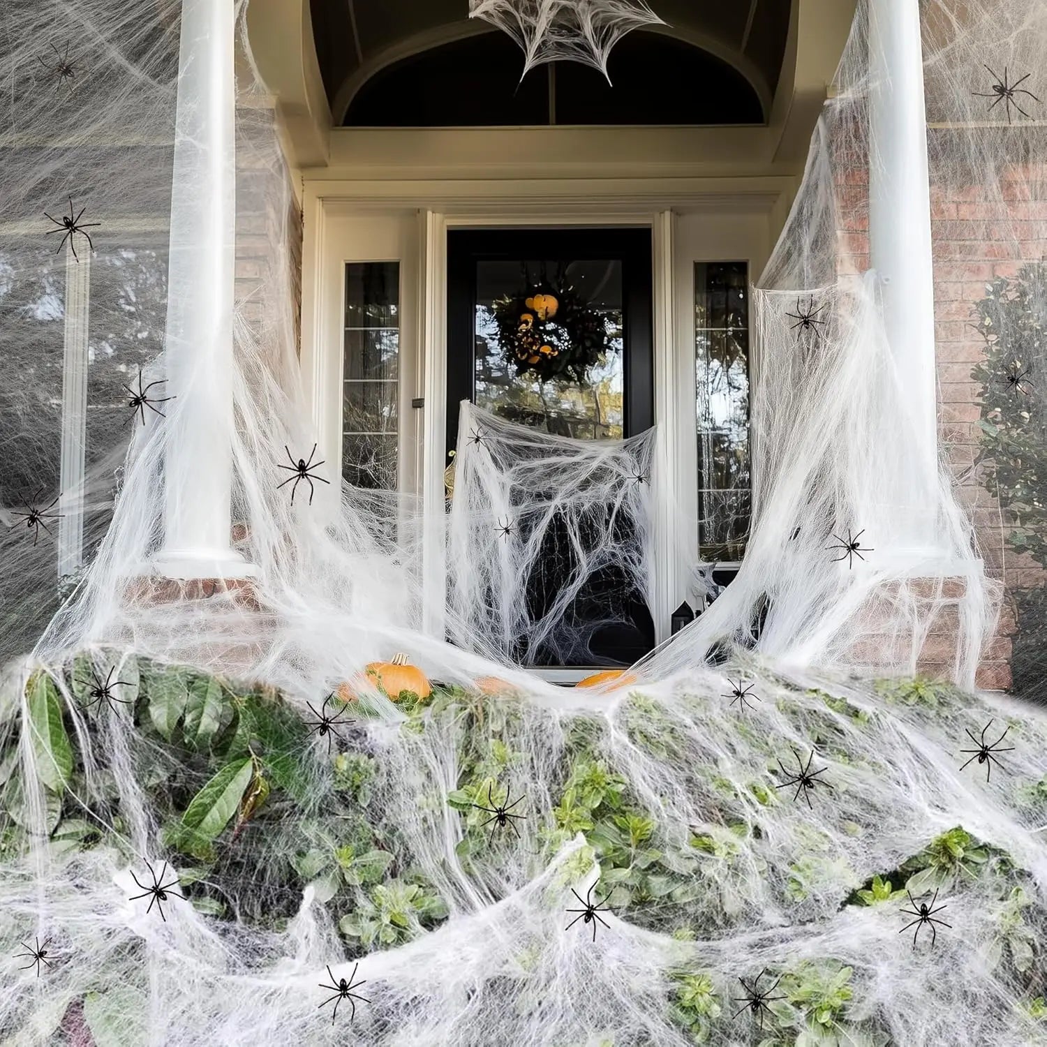 Halloween-themed outdoor decoration with spider webs, spiders, and a door in the background.