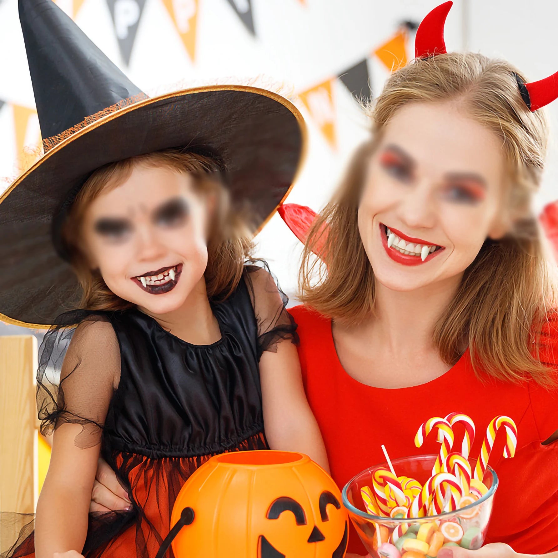 Woman and child in Halloween costumes with candy and a pumpkin.